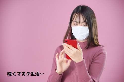 マスクをしながらスマートフォンを触る女性